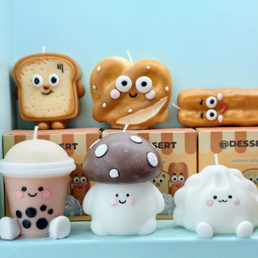 Cute food-shaped candles including toast, pretzel, churro, bubble tea, mushroom, and dumpling characters, all with smiling faces and pastel colors.